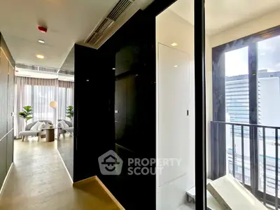 Modern apartment hallway with glass doors and city view, leading to a stylish living room.