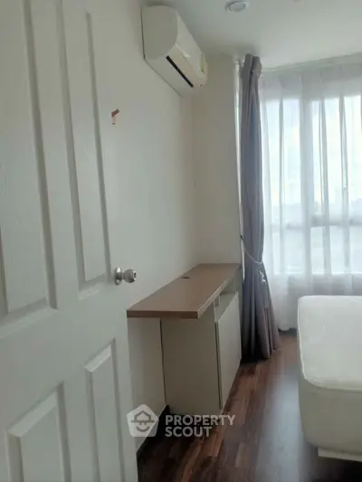 Cozy bedroom with natural light, wooden flooring, and air conditioning