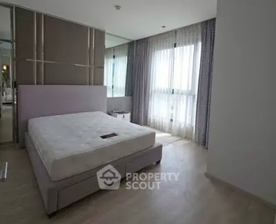 Spacious bedroom with large windows and modern decor in a bright apartment.