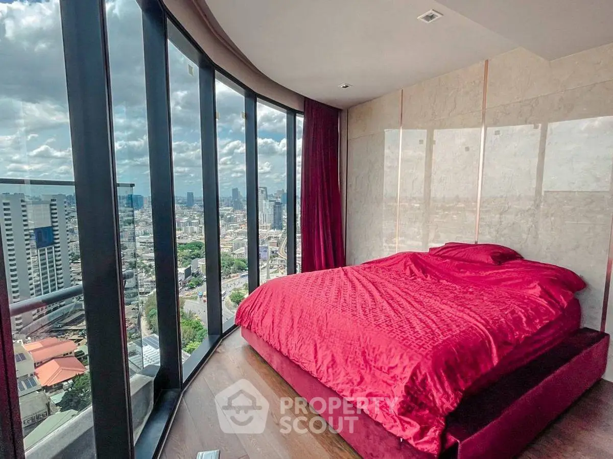 Luxurious bedroom with panoramic city view and elegant red bedding.