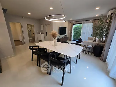 Modern dining area with elegant table and chairs, open to a cozy living room with natural light.