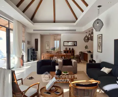 Spacious living room with high ceiling and modern decor, featuring large windows and elegant furniture.