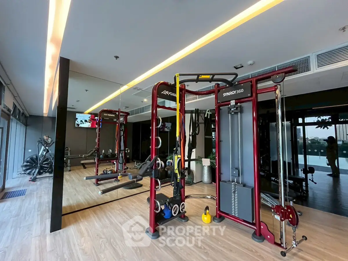Modern gym with state-of-the-art fitness equipment and mirrored walls in luxury apartment complex.