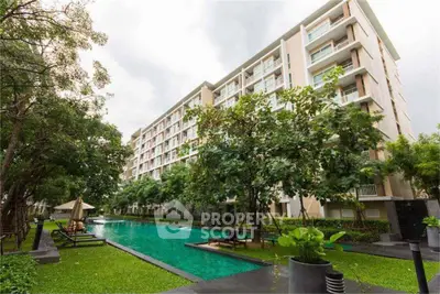 Luxurious apartment building with serene pool and lush greenery