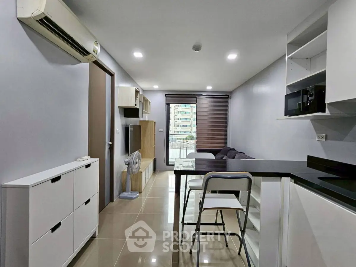 Modern open-plan living room with sleek kitchen and balcony view