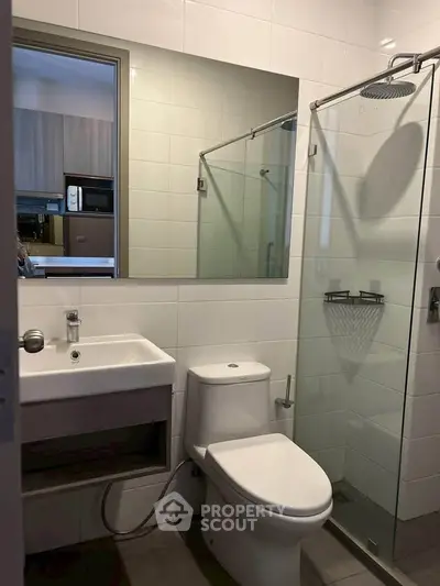 Modern bathroom with glass shower and sleek fixtures in contemporary apartment.