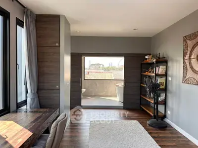 Spacious modern living area with wooden floors and city view, featuring a cozy reading nook and stylish decor.