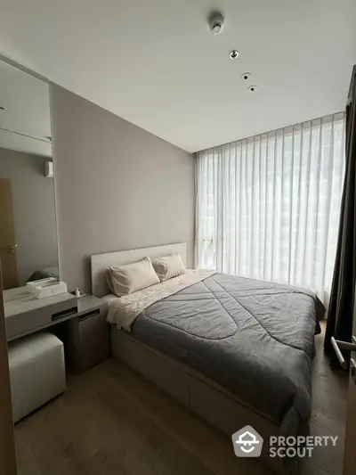 Modern bedroom with cozy bed and natural light through sheer curtains