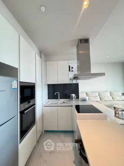 Modern kitchen with sleek white cabinets and built-in appliances in open layout