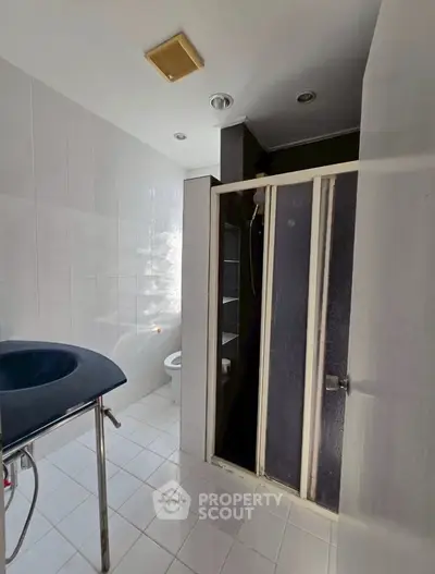 Modern bathroom with sleek shower and stylish sink in a bright, tiled space.