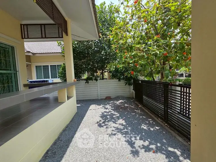 Charming outdoor space with lush greenery and modern fence in a serene residential area.