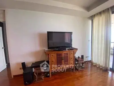 Spacious living room with elegant wooden TV stand and large flat-screen TV, featuring floor-to-ceiling curtains.