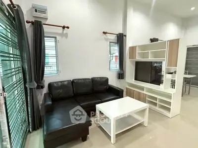 Modern living room with black leather sofa and sleek entertainment unit