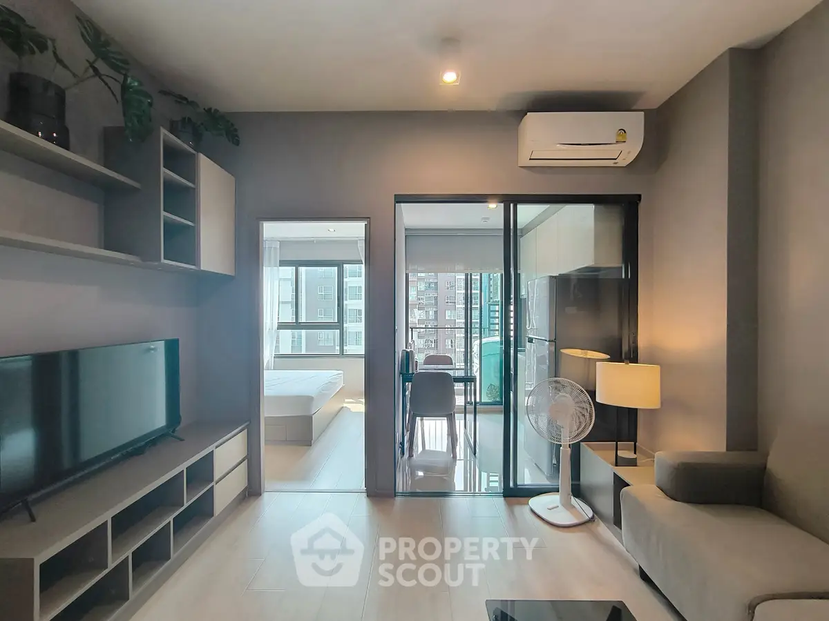 Modern living room with sleek design and open view to bedroom and kitchen.