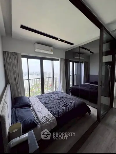 Luxurious bedroom with stunning city view and mirrored wardrobe in modern apartment.