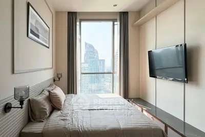 Modern bedroom with city view, featuring sleek design and large window for natural light.