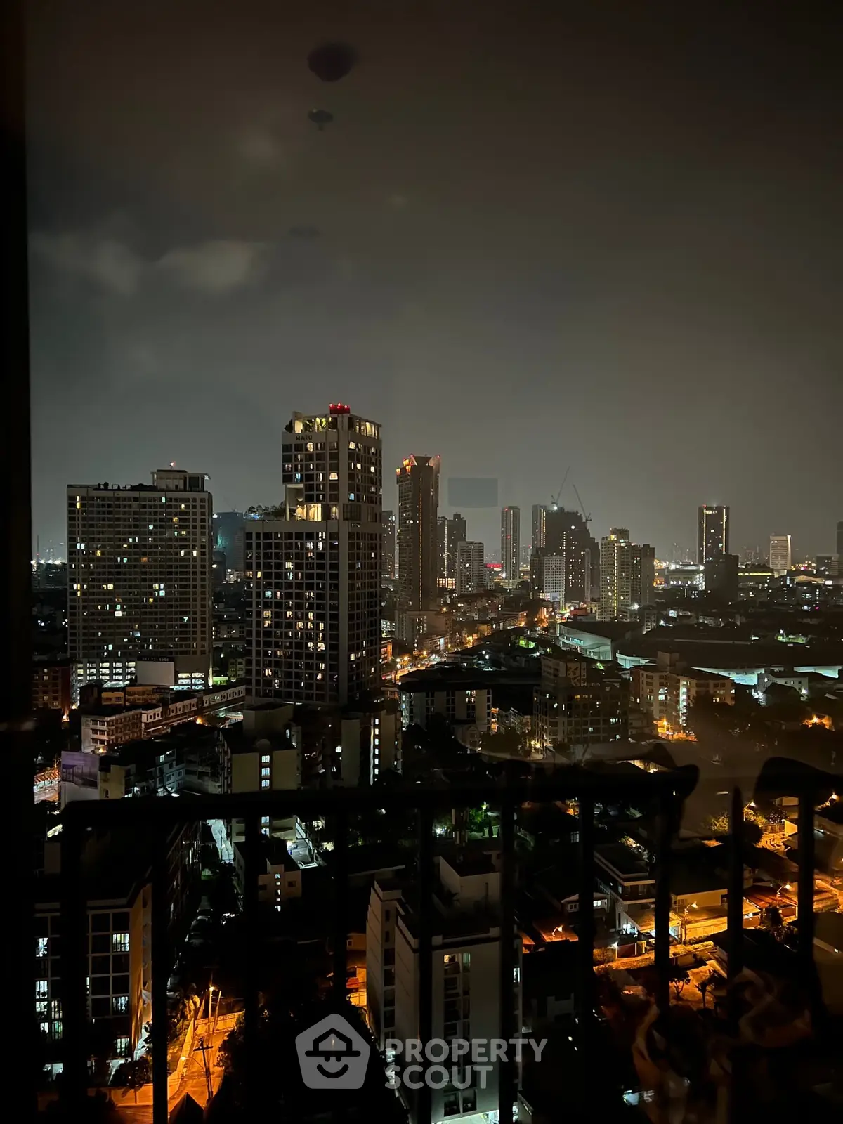 Stunning nighttime cityscape view from a high-rise balcony, showcasing vibrant urban lights and skyline.