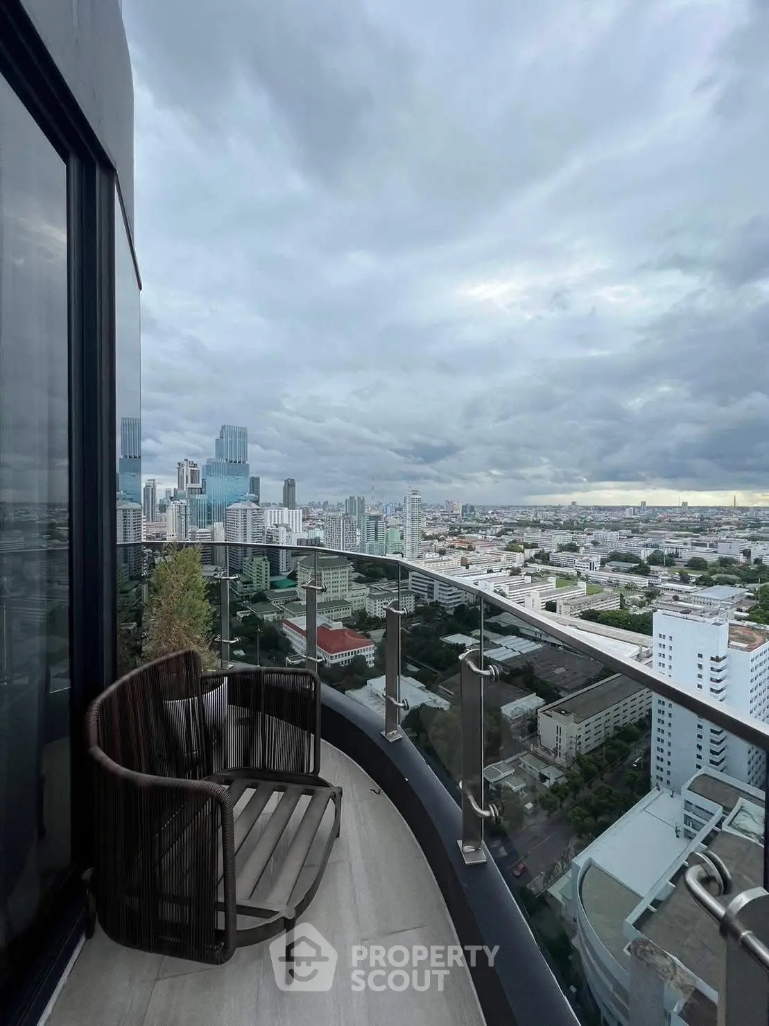 Stunning cityscape view from a modern high-rise balcony with sleek glass railing.