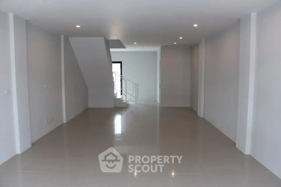 Spacious open-plan living area with modern staircase and sleek tile flooring.