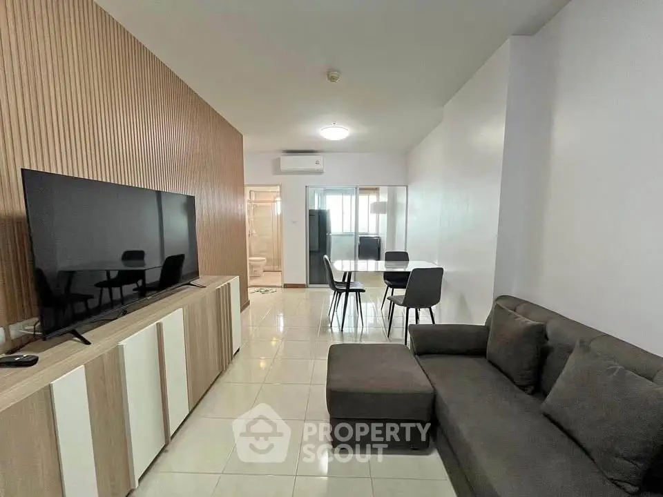 Modern living room with sleek furniture and large TV in a stylish apartment.