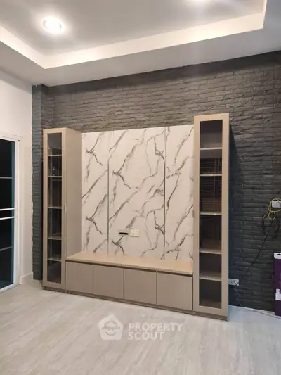 Modern living room with stylish marble accent wall and built-in storage units.