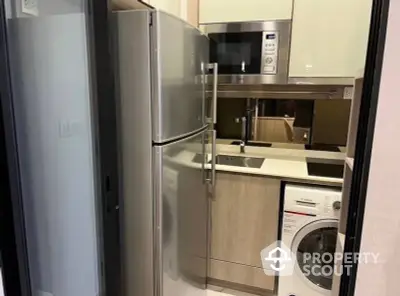 Compact modern kitchen with stainless steel appliances and washing machine