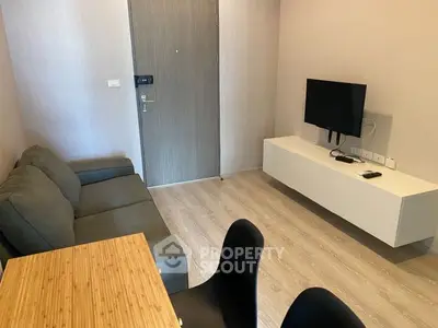 Modern living room with sleek furniture and wall-mounted TV in cozy apartment.
