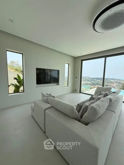 Modern living room with panoramic view and sleek design, featuring a cozy gray sofa and large windows.