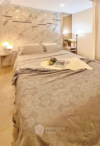 Luxurious bedroom with elegant marble accent wall and cozy bedding in modern apartment.