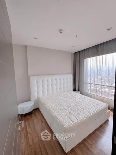 Spacious bedroom with large window offering stunning city views, featuring a modern bed and elegant decor.