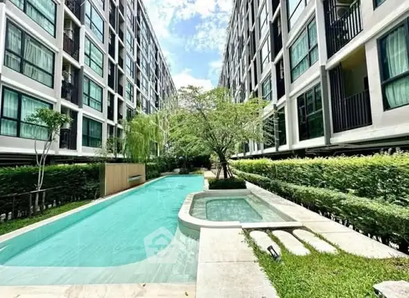 Modern condominium with lush garden and inviting swimming pool view.