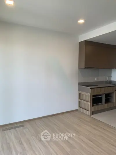Modern open kitchen with sleek cabinetry and wood flooring in a bright apartment.