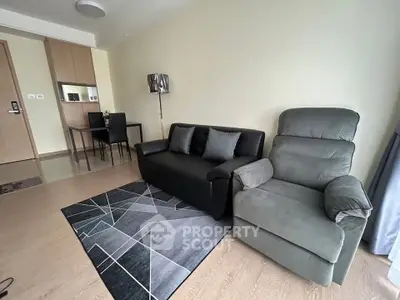 Modern living room with stylish sofa and armchair, featuring a sleek dining area and contemporary decor.
