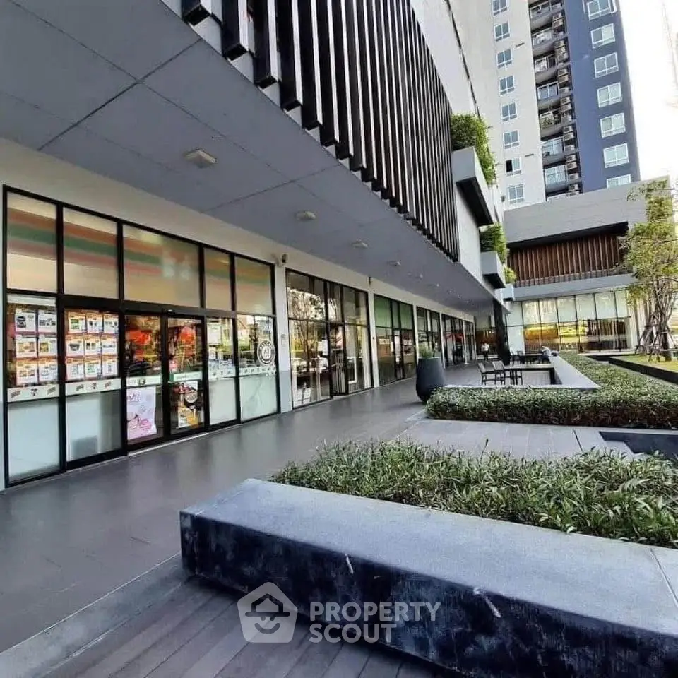 Modern building exterior with landscaped garden and seating area, perfect for urban living.