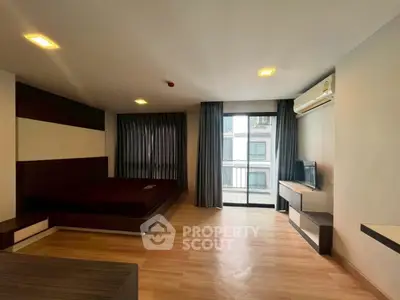 Spacious modern bedroom with balcony access and sleek wooden flooring.