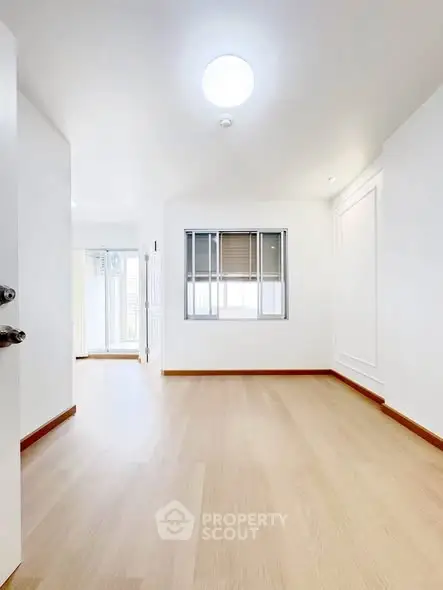 Spacious empty room with wooden flooring and bright natural light