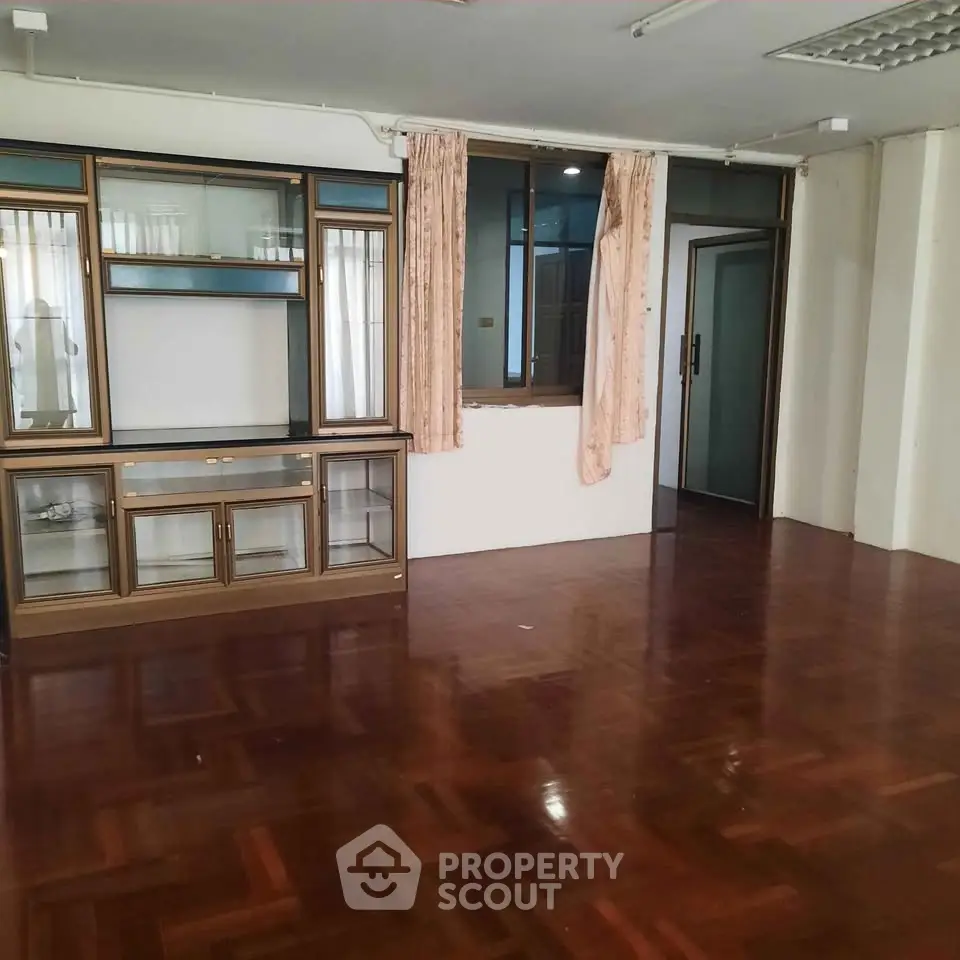 Spacious empty living room with wooden floors and built-in shelving unit.