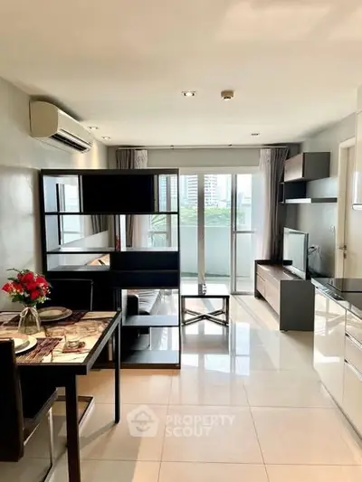 Modern living room with open layout and balcony view, featuring sleek furniture and natural light.
