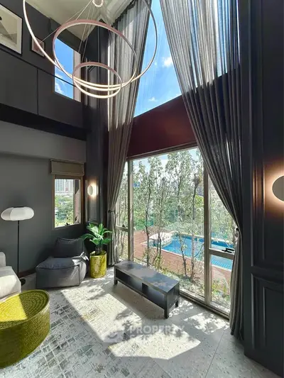 Luxurious living room with floor-to-ceiling windows and pool view, featuring modern decor and high ceilings.