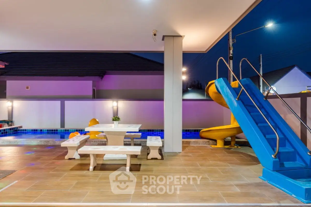 Luxurious outdoor pool area with slide and seating, perfect for family entertainment.