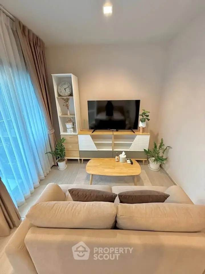 Cozy living room with modern decor, featuring a beige sofa, wooden coffee table, and entertainment center.