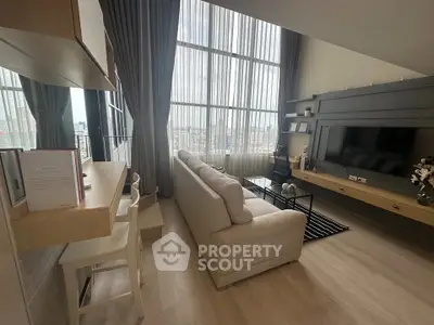 Modern living room with high ceilings and large windows offering city views.