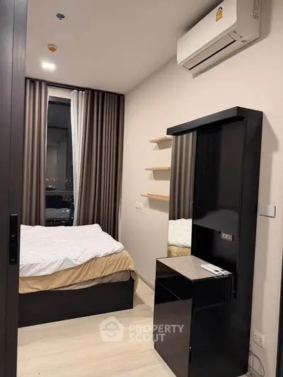 Modern bedroom with sleek black furniture and large window offering city view.