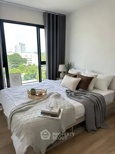 Cozy bedroom with large window and stylish decor in modern apartment