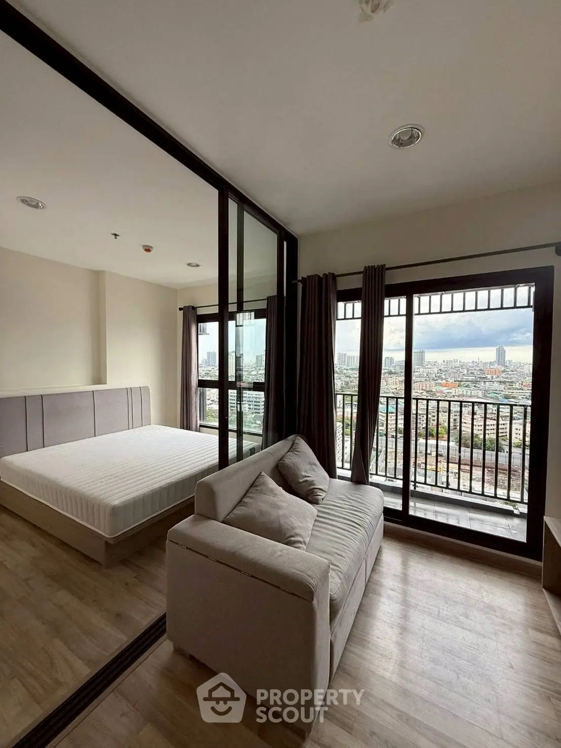Modern apartment with city view, featuring a cozy living area and spacious bedroom with large windows.
