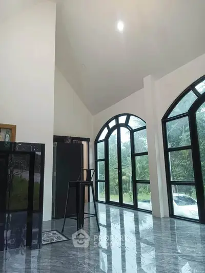 Spacious modern interior with large arched windows and sleek marble flooring.