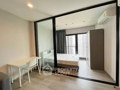 Modern bedroom with sliding glass doors and city view balcony in a high-rise apartment.
