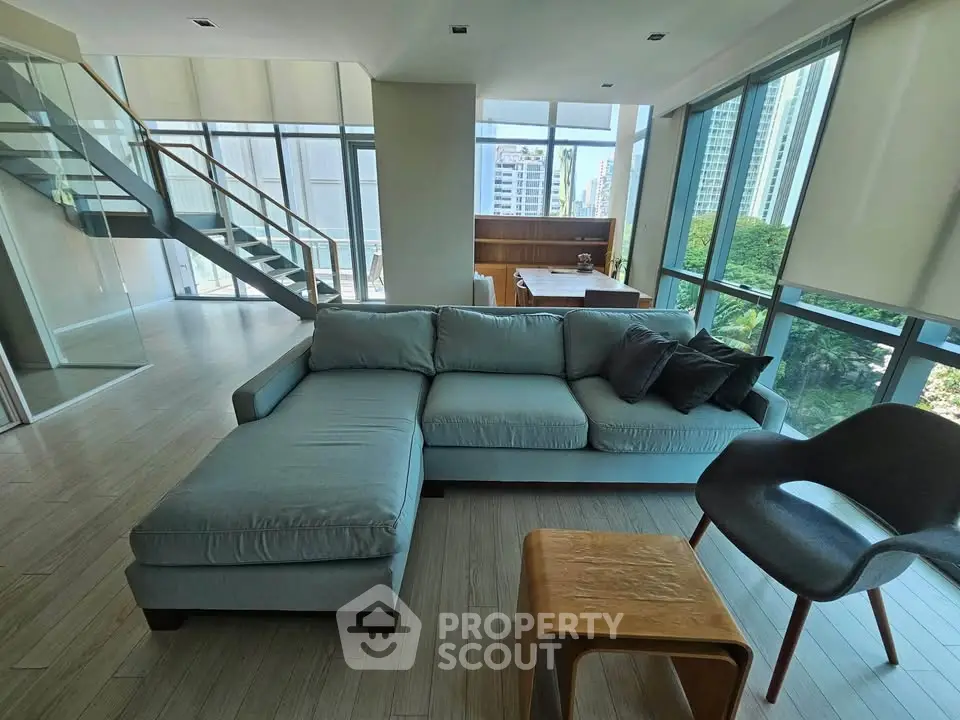 Spacious modern living room with large windows and city view, featuring stylish furniture and open layout.