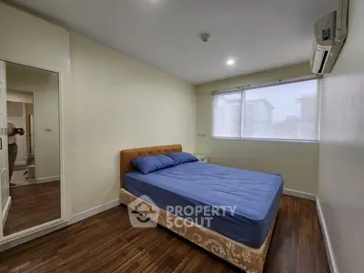Spacious bedroom with large window and modern air conditioning unit, featuring a comfortable bed and wooden flooring.