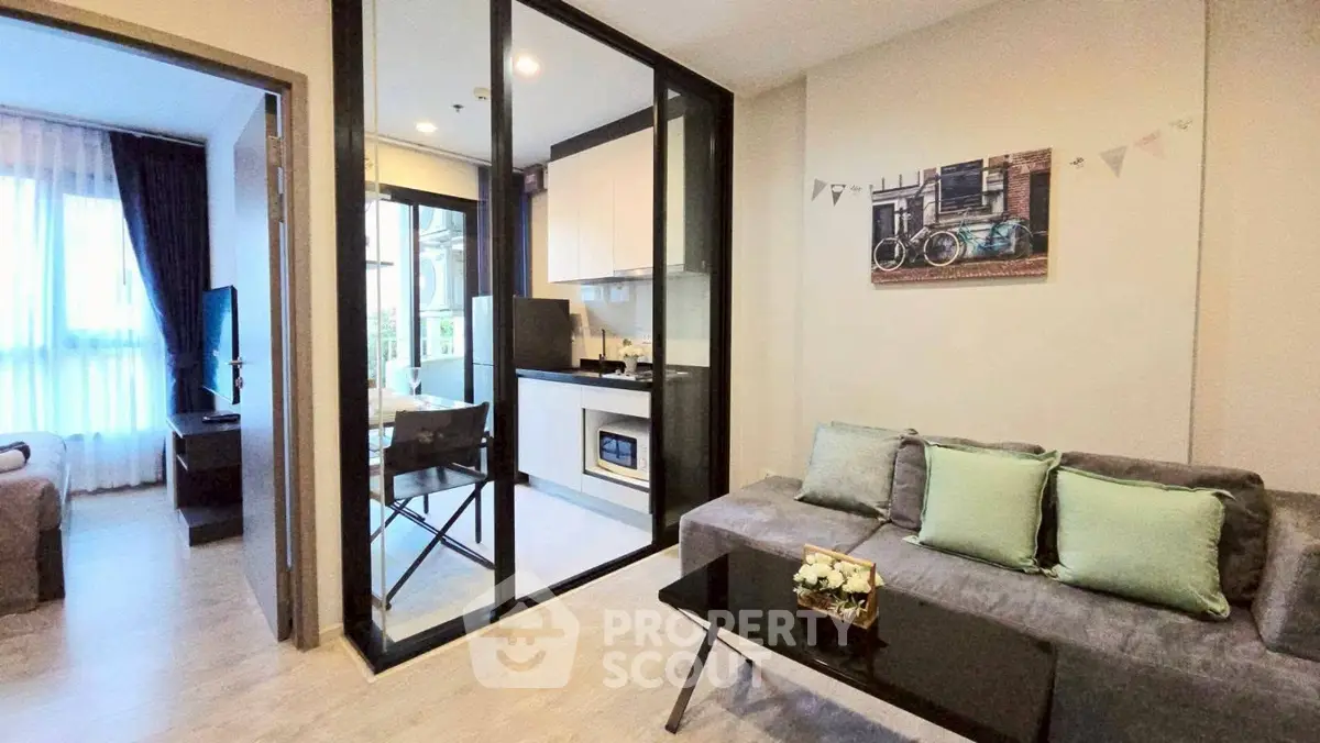 Modern living room with glass partition and cozy kitchen area in stylish apartment.